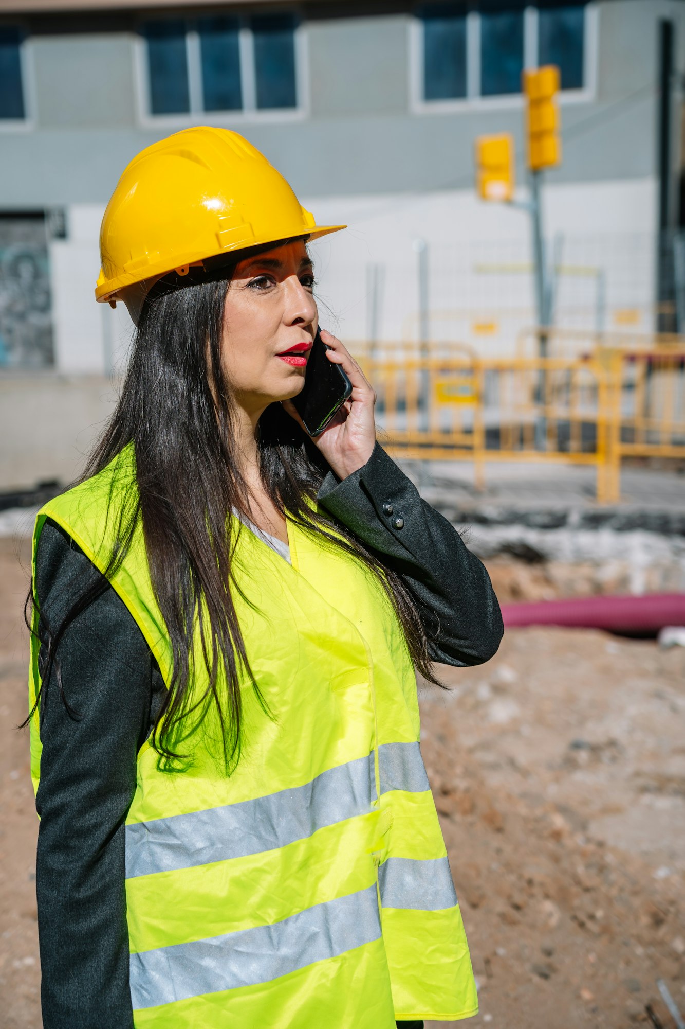 Happy Hispanic female inspector having phone conversation at construction site